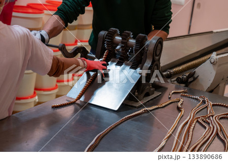 Close-up view of caramel candy making in a factory, showing warm melted sugar being shaped and crafted into sweet treats. Close-up view of caramel candy making in a factory, showing warm melted sugar being shaped and crafted into sweet treats. 133890686