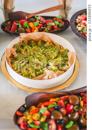 Fresh and colorful vegetarian meal with hummus, mixed green salad, tomatoes, cucumbers, and other vegetables beautifully arranged on a white background. Clean, minimalistic, and healthy food concept. Fresh and colorful vegetarian meal with hummus, mixed green salad, tomatoes, cucumbers, and other vegetables beautifully arranged on a white background. Clean, minimalistic, and healthy food concept. 133890855
