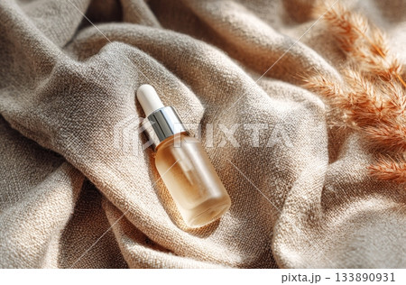 Natural essence serum dropper bottle on fabric with plants 133890931