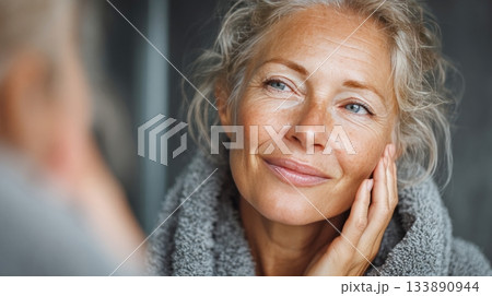 Mature woman seeing reflection feeling good about skincare 133890944