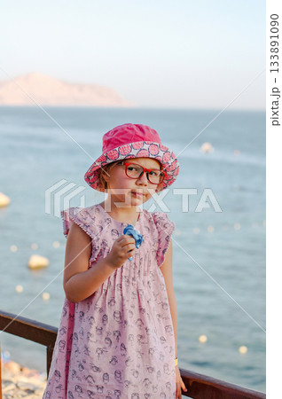 Little adorable child girl enjoying summer in the beach. Eating icecream Little adorable child girl enjoying summer in the beach. Eating icecream 133891090