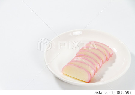 白背景の白い皿に盛り付けられた紅白のかまぼこ、おせち料理・和食のシンプル素材 133892593
