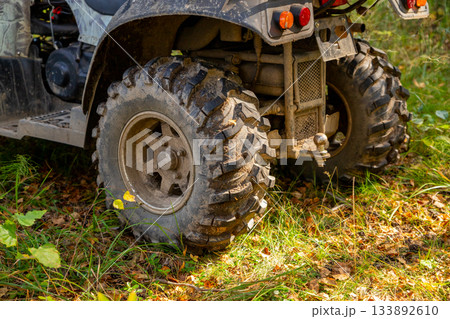 rear wheels of ATV on grass in forest in summer. quad bike or All Terrain Vehicle 133892610