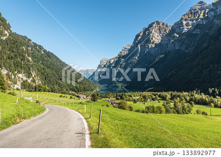 Road with scenic view of Kloentalersee (Lake Kloental) in the Swiss Alps, Canton Glarus, Switzerland Road with scenic view of Kloentalersee (Lake Kloental) in the Swiss Alps, Canton Glarus, Switzerland 133892977