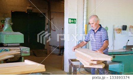 Senior carpenter working with wood in workshop 133893374