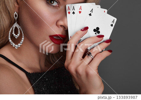 Blonde lady woman in black shiny dress and expensive diamond jewelry is winner money from Omaha Holdem. She is smiling, showing Aces cards to the camera. Ideal style for Poker, Casino, Gambling Blonde lady woman in black shiny dress and expensive diamond jewelry is winner money from Omaha Holdem. She is smiling, showing Aces cards to the camera. Ideal style for Poker, Casino, Gambling 133893987