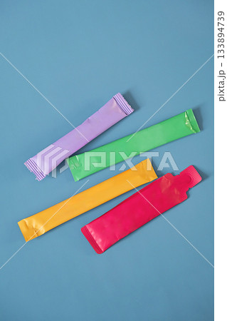 Colorful sachets packets on blue background with empty space for design. Colorful sachets packets on blue background with empty space for design. 133894739