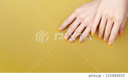 Beautiful Female Hands with bright orange Manicure like Candy Corn. Manicured Nails with Yellow Gel Polish. Halloween Style 133894935