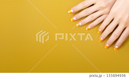 Beautiful Female Hands with bright orange Manicure like Candy Corn. Manicured Nails with Yellow Gel Polish. Halloween Style 133894936
