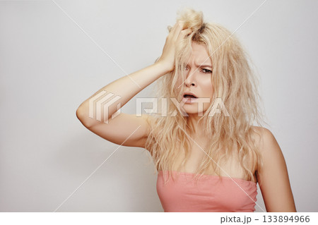 Beautiful woman with messed up hair. Unhappy grimacing face. Blond bleaching hairstyle with problem brittle hair 133894966
