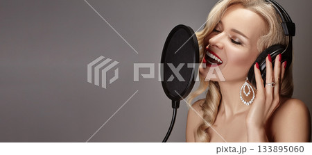 Blonde Woman Singing Song in Recording Studio with Microphone, Headphones. Glamour Diva Creates Musical Track. Karaoke Blonde Woman Singing Song in Recording Studio with Microphone, Headphones. Glamour Diva Creates Musical Track. Karaoke 133895060