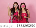 Party Celebration. Two joyful women enjoying a festive moment with drinks and decorations. 133895250