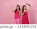Party Vibes. Two women celebrating with drinks and a bottle in a playful atmosphere. 133895254
