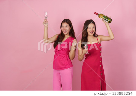 Party Vibes. Two women celebrating with drinks and a bottle in a playful atmosphere. 133895254