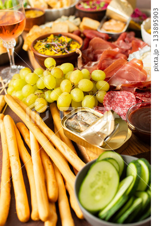 Gathered around a beautifully arranged charcuterie board filled with assorted cheeses, delicious sausages, creamy hummus, and fresh grapes. Perfect for a small gathering 133895903
