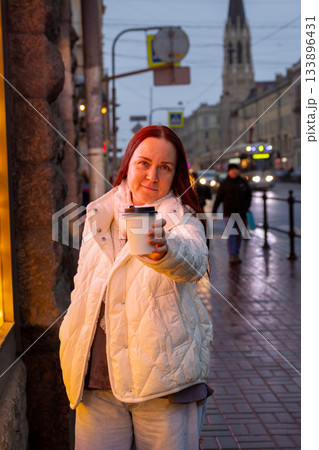 A Caucasian woman gives a cup of aromatic coffee to a camera under neon lights. Date A Caucasian woman gives a cup of aromatic coffee to a camera under neon lights. Date 133896431