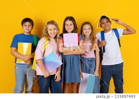 Group of preteen children posing with school notebooks in bright studio background Group of preteen children posing with school notebooks in bright studio background 133897493