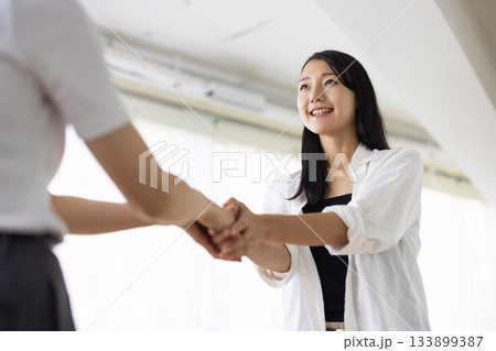 笑顔で握手を交わす女性 133899387