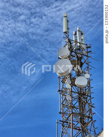 A large communication tower (communication tower) with numerous antennas and satellite dishes, photographed against a bright blue sky. A large communication tower (communication tower) with numerous antennas and satellite dishes, photographed against a bright blue sky. 133900152