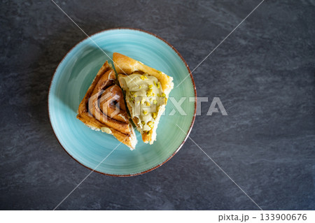 Pistachio cinnamon roll halves on an artisan plate in a home kitchen, top view. Natural light and simple setup show homemade dessert details. Concept of breakfast, pastry, comfort, homemade. Pistachio cinnamon roll halves on an artisan plate in a home kitchen, top view. Natural light and simple setup show homemade dessert details. Concept of breakfast, pastry, comfort, homemade. 133900676