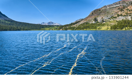 Aerial Pristine Lake Blue Water Mountain Forest and Rocky Slopes Summer 133901244