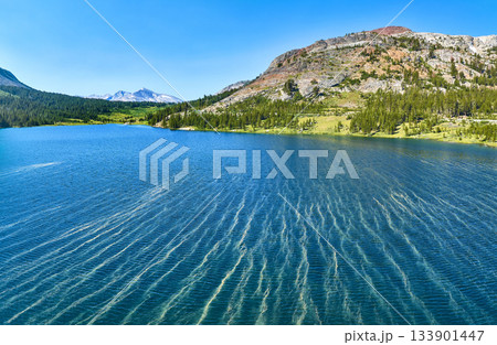 Aerial Pristine Lake Mountain Forest and Rocky Slope Panorama Under Blue Sky 133901447