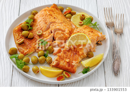 roasted salmon fillet on plate with green olives 133901553