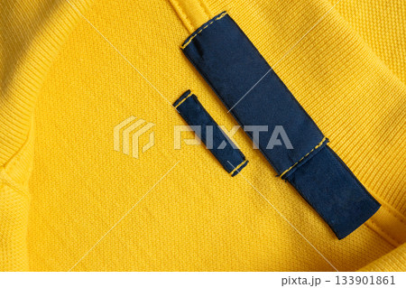 Blank blue laundry care clothes label on yellow shirt fabric texture background Blank blue laundry care clothes label on yellow shirt fabric texture background 133901861