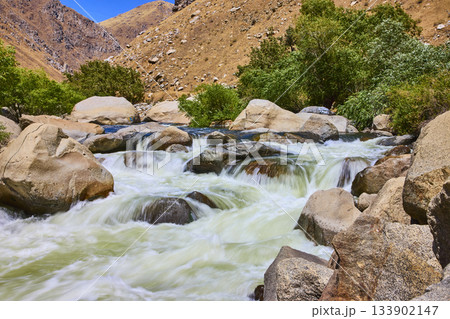 Kern River Rapids Flowing Over Rocks with Green Trees and Arid Hills Kern River Rapids Flowing Over Rocks with Green Trees and Arid Hills 133902147