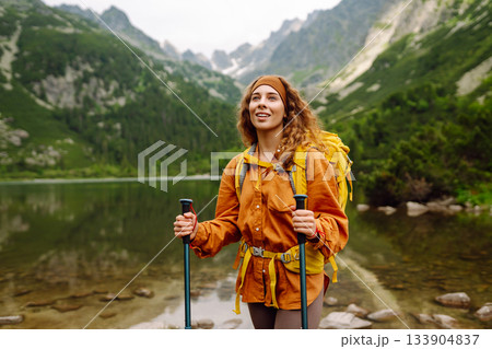 Travel Slovakia, Europe. Tourist with a yellow backpack stands against the backdrop of alpine lake. Travel Slovakia, Europe. Tourist with a yellow backpack stands against the backdrop of alpine lake. 133904837
