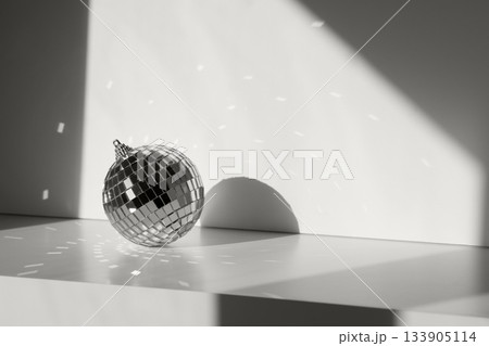 Disco ball in sunlight with reflections on minimal background. Geometric shadows color of 2026 year cloud white Disco ball in sunlight with reflections on minimal background. Geometric shadows color of 2026 year cloud white 133905114