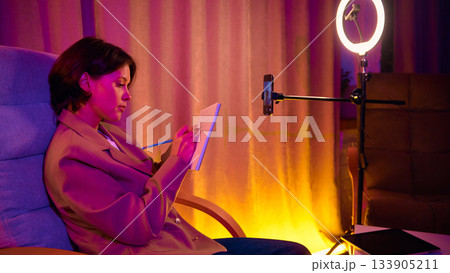 Woman holding notebook and filming coaching speech on phone. Woman holding notebook and filming coaching speech on phone. 133905211