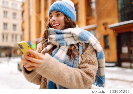 Woman is walking in city, viewing social nets in smartphone. Lifestyle, travel, tourism, technology 133905293