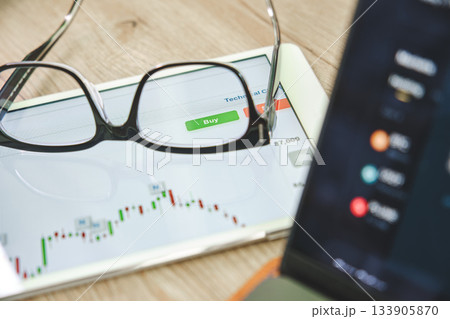 Glasses resting on tablet displaying stock market chart and buy button Glasses resting on tablet displaying stock market chart and buy button 133905870