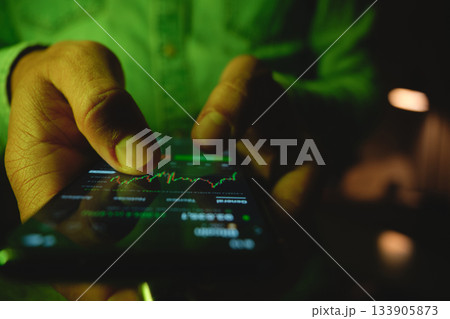 Hand trading stock market investments on smartphone screen Hand trading stock market investments on smartphone screen 133905873
