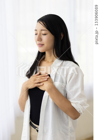 窓辺で胸に手を当て微笑む女性 133906089