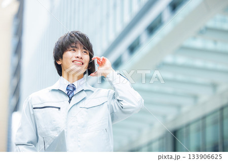 スマホで通話する作業服の男性 133906625
