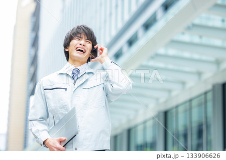 スマホで通話する作業服の男性 133906626