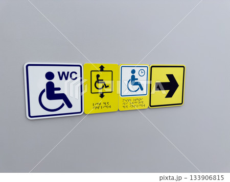 Set of accessible area signs on wall. Wheelchair user sign with arrow sign pointing to accessible elevator and restroom for people with mobility issues Set of accessible area signs on wall. Wheelchair user sign with arrow sign pointing to accessible elevator and restroom for people with mobility issues 133906815