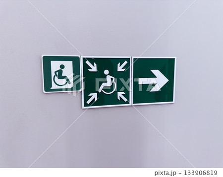 Set of green signs with arrows indicating direction of way for wheelchair users. Accessibility issues are addressed through creation of accessible environment and directional signs on wall Set of green signs with arrows indicating direction of way for wheelchair users. Accessibility issues are addressed through creation of accessible environment and directional signs on wall 133906819