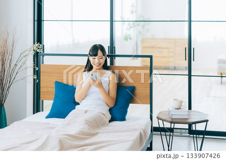 ベッドでスマホを見る若い女性 133907426