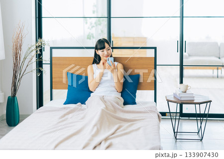 ベッドでスマホを見る若い女性 ベッドでスマホを見る若い女性 133907430