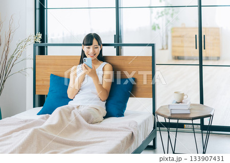 ベッドでスマホを見る若い女性 ベッドでスマホを見る若い女性 133907431