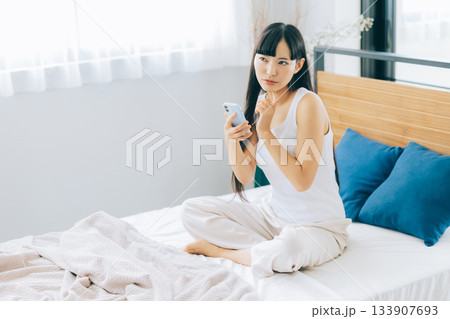 ベッドでスマホを見る若い女性 133907693