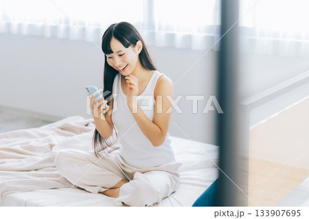 ベッドでスマホを見る若い女性 133907695