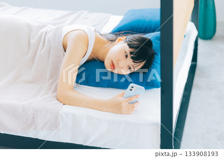 ベッドでスマホを見る若い女性 133908193