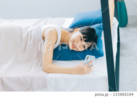 ベッドでスマホを見る若い女性 133908194