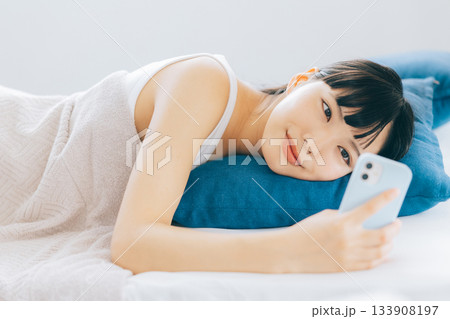 ベッドでスマホを見る若い女性 133908197