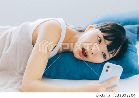 ベッドでスマホを見る若い女性 133908204
