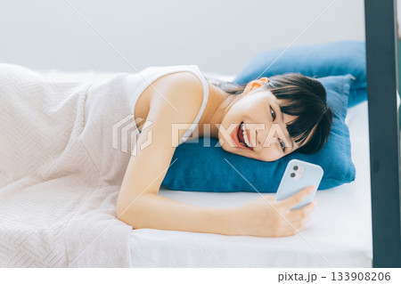 ベッドでスマホを見る若い女性 ベッドでスマホを見る若い女性 133908206
